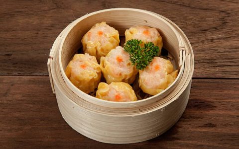 Chinese dim sum in a bamboo steamer box on a wood table